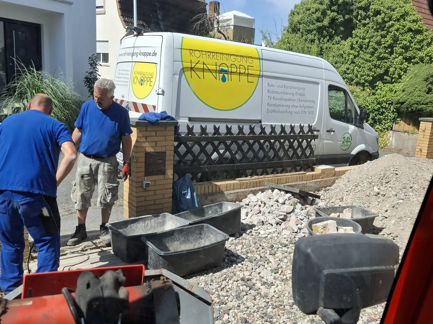 Einsatzfahrzeug und Material an einer Baustelle vor einem Wohnhaus