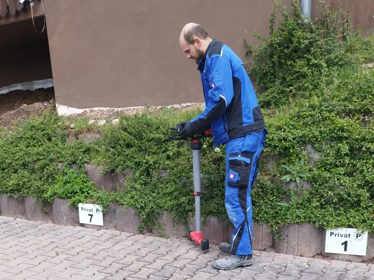 Mitarbeiter bei der Ortung einer Abwasserleitung auf einem gepflasterten Hof