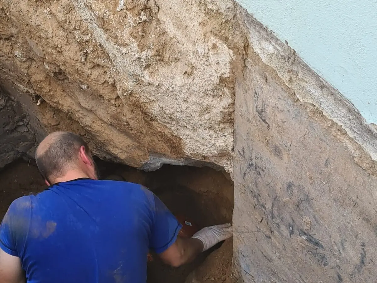 Freigelegte Abwasserleitung an einer Hauswand beim Einbau einer Rückstausicherung