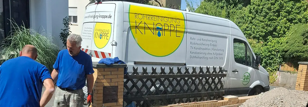Zwei Mitarbeiter von Rohrreinigung Knappe bei der Arbeit vor dem Firmenfahrzeug